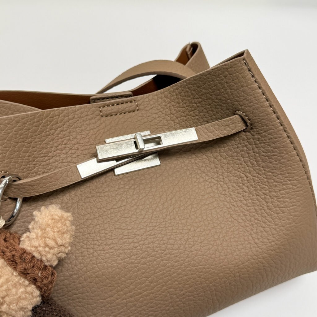 Close-up of a metal clasp on a taupe handbag