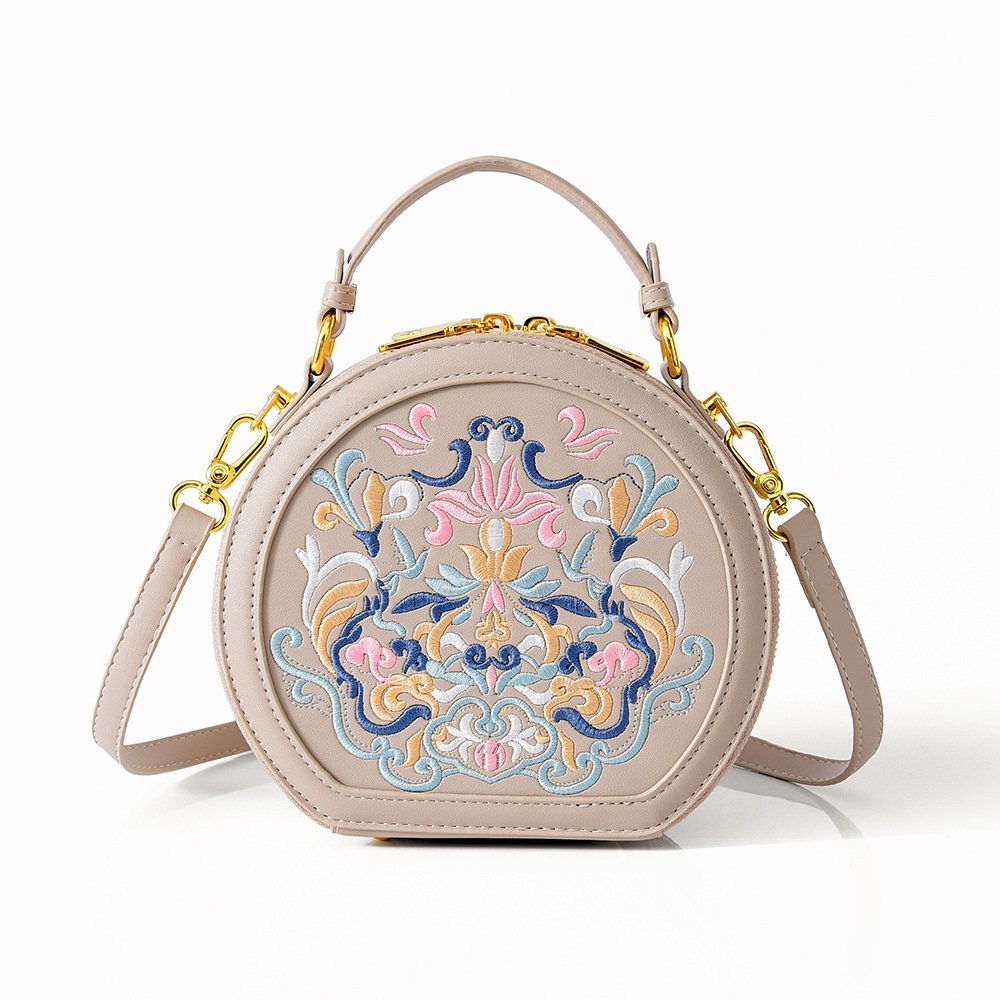 Round beige handbag with multicolor embroidered front panel