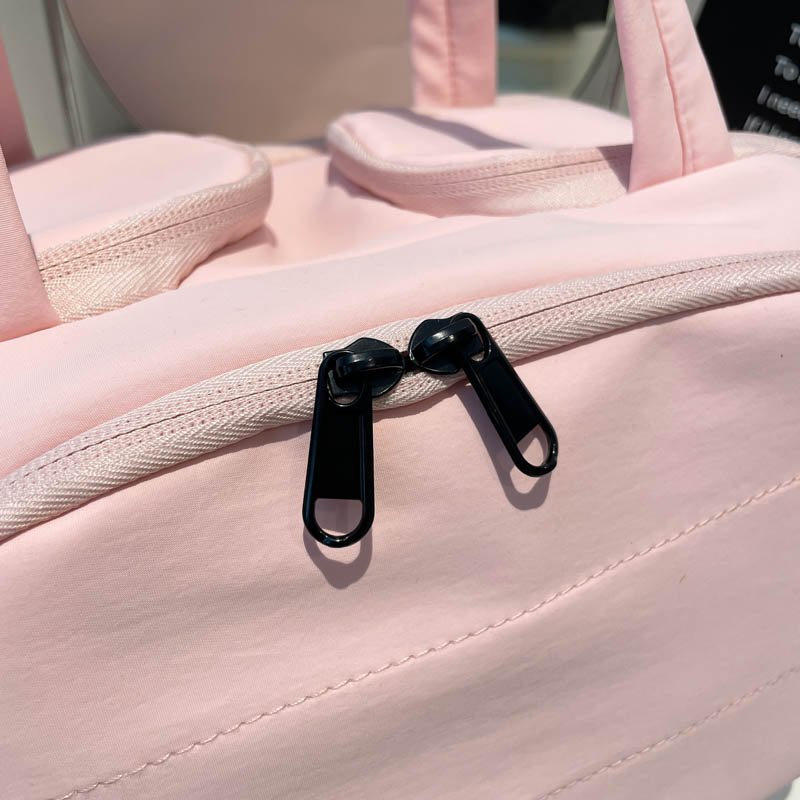 Close-up of black zipper pulls on a pink cosmetic bag