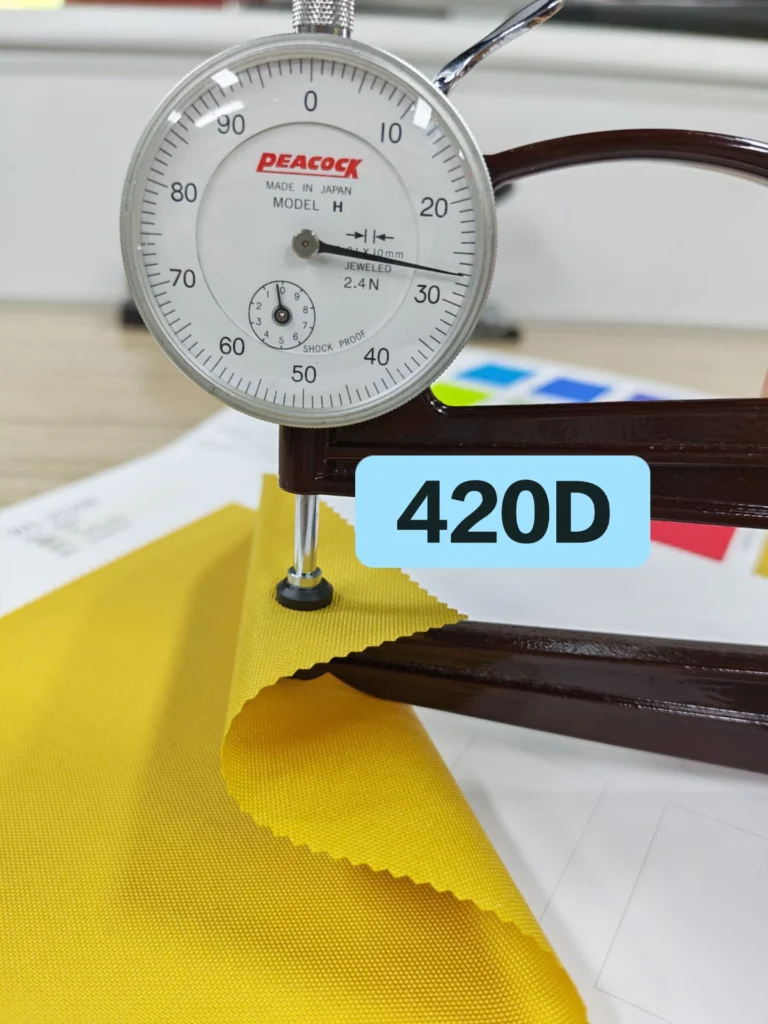 Thickness gauge contacting a yellow fabric swatch labelled 420D