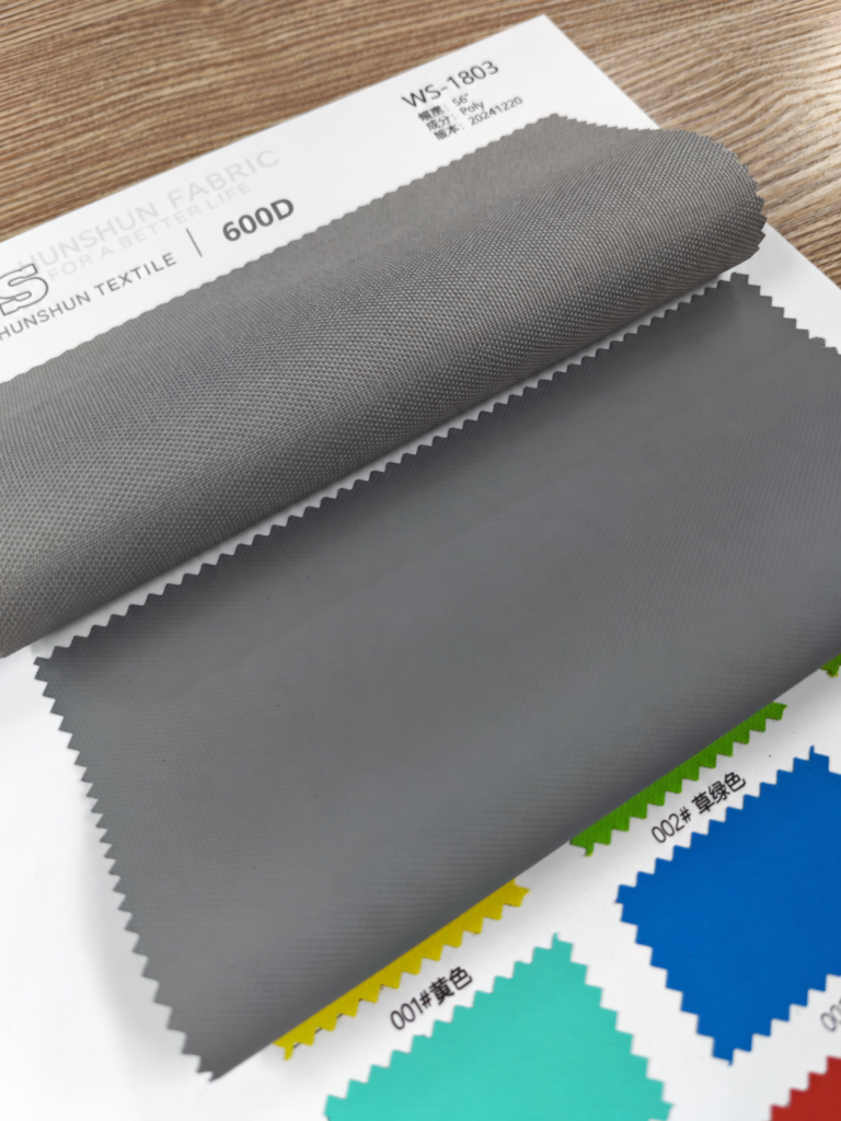 Grey fabric swatch folded to reveal its woven face and reverse on a sample card